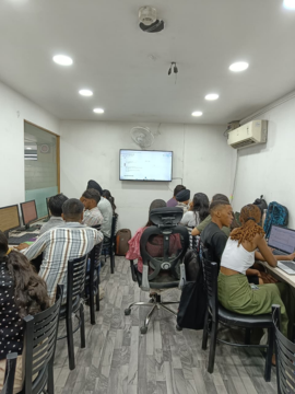 The classroom seen from the back, every seat taken and the front screen running