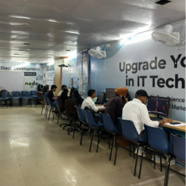 Students at their machines on the lab floor with a trainer alongside